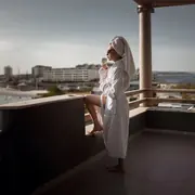 Model in a white robe on a hotel balcony