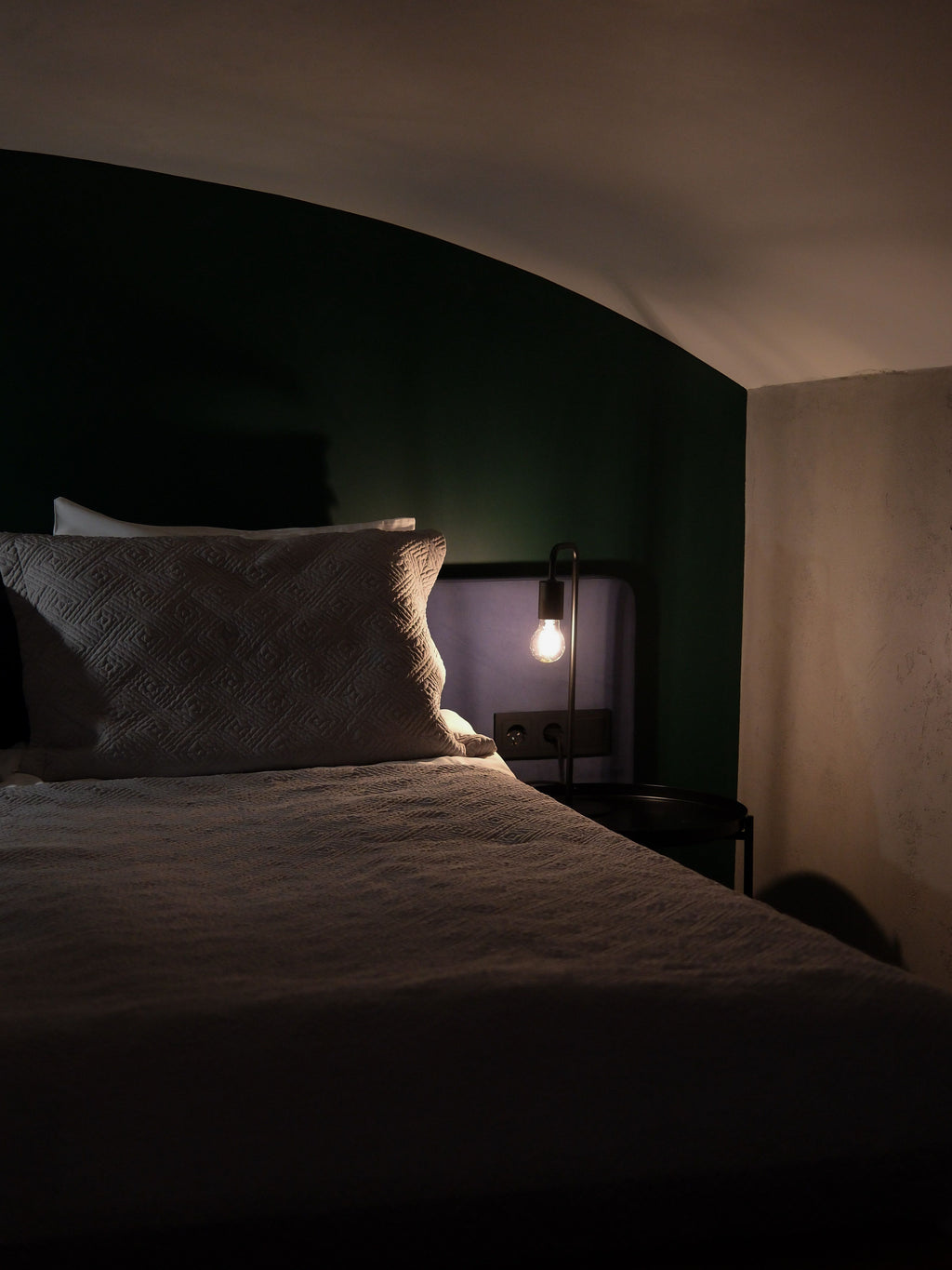 A dim, quiet bedroom at night with a single warm lamp before sleep