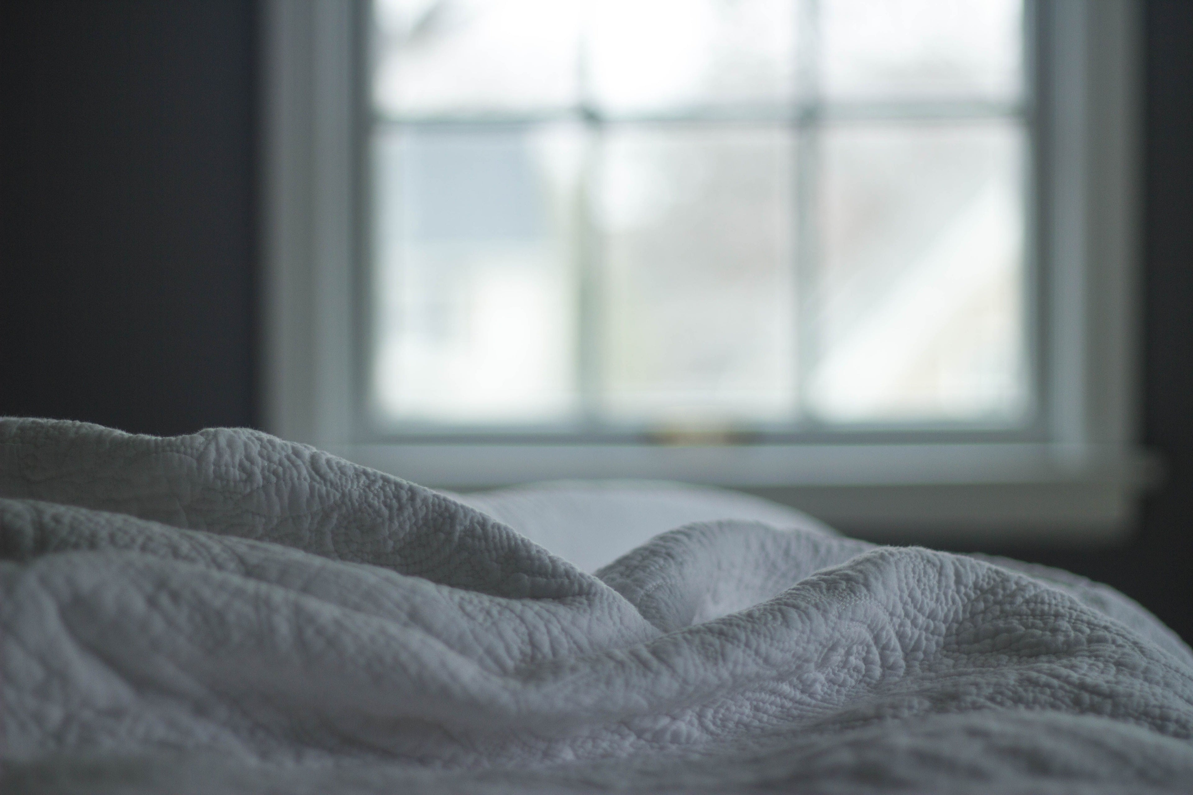 Soft quilted bedding lit by morning window light — the calm, restful atmosphere the Driftnest mask is designed for