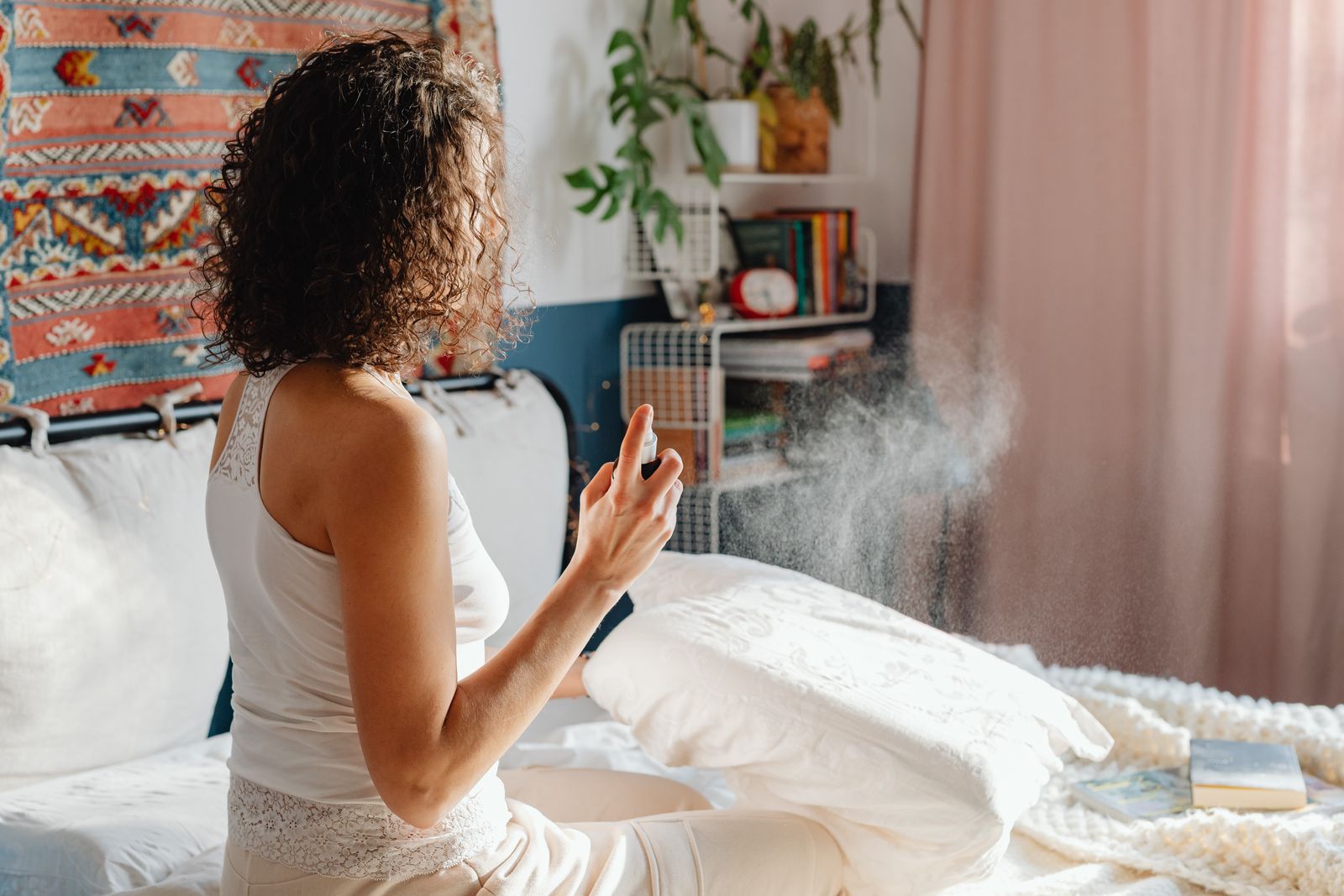 A woman misting her pillow as part of a calming bedtime routine